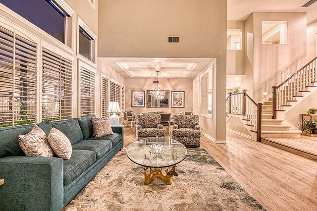 5 Kennedy Ct, Coto De Caza, CA 92679 - living room featuring wood finished floors, coffered ceiling, stairs, a chandelier, and a high ceiling