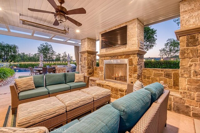 5 Kennedy Ct, Coto De Caza, CA 92679 - patio terrace at dusk with an outdoor living space with a fireplace, a patio, exterior kitchen, and a ceiling fan
