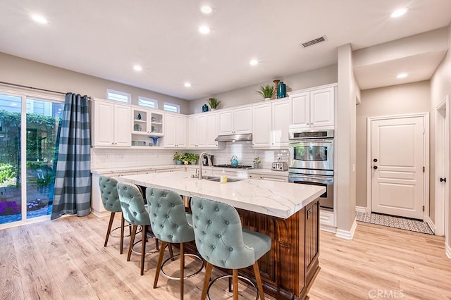 5 Kennedy Ct, Coto De Caza, CA 92679 - kitchen featuring double oven, under cabinet range hood, light wood-type flooring, white cabinets, and recessed lighting
