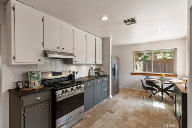 8 Barton Pkwy, Oakdale, CA 95361 - kitchen featuring appliances with stainless steel finishes, under cabinet range hood, dark countertops, white cabinets, and tasteful backsplash