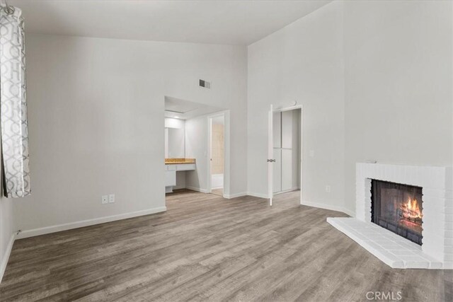 1077 Santo Antonio Dr Unit 54, Colton, CA 92324 - unfurnished living room featuring wood finished floors, a brick fireplace, and high vaulted ceiling