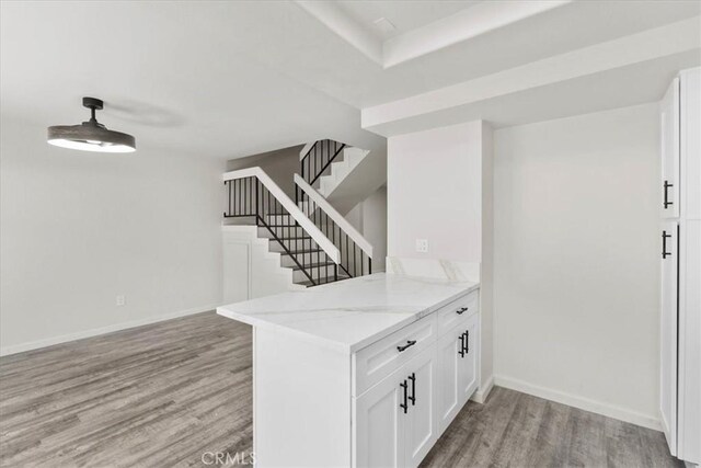 1077 Santo Antonio Dr Unit 54, Colton, CA 92324 - interior space with light wood-style flooring, light stone counters, white cabinets, and a peninsula