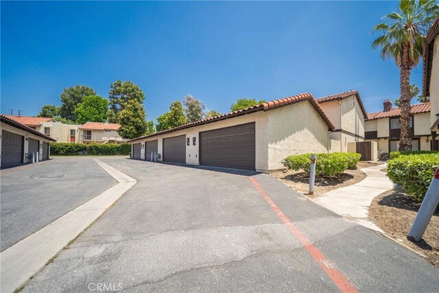 1077 Santo Antonio Dr Unit 54, Colton, CA 92324 - view of front facade with community garages, stucco siding, a tiled roof, and a residential view