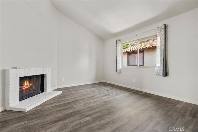 1077 Santo Antonio Dr Unit 54, Colton, CA 92324 - unfurnished living room featuring vaulted ceiling, wood finished floors, and a brick fireplace