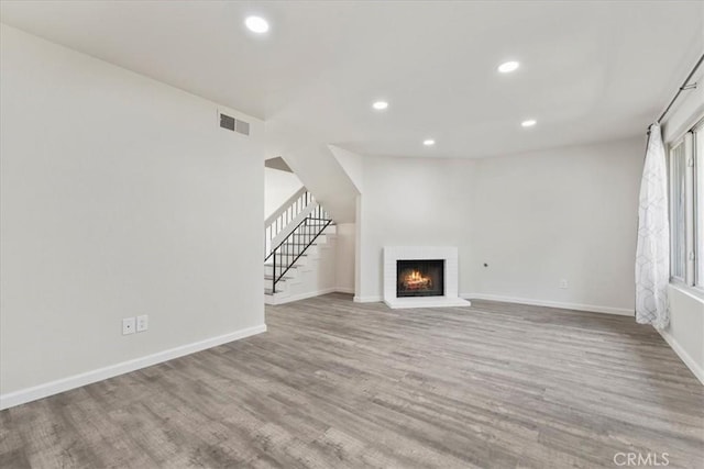 1077 Santo Antonio Dr Unit 54, Colton, CA 92324 - unfurnished living room featuring wood finished floors, a brick fireplace, recessed lighting, and stairs