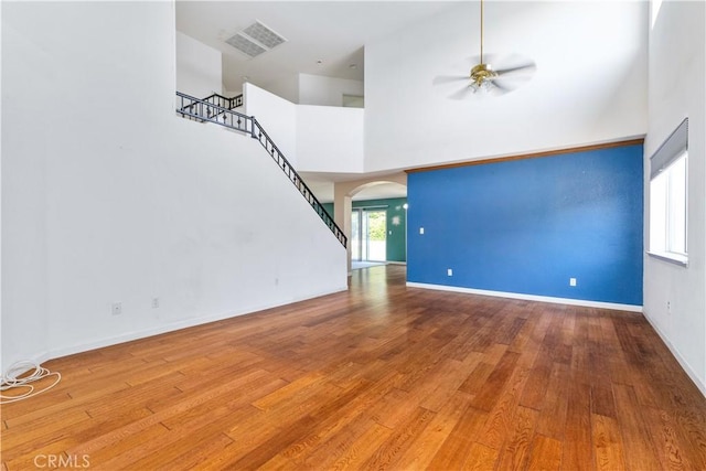 1678 Bella Vista Ct, Paso Robles, CA 93446 - unfurnished living room featuring ceiling fan, arched walkways, stairway, wood finished floors, and a high ceiling