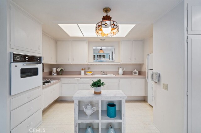 1670 Interlachen Rd Unit 43J, Seal Beach, CA 90740 - kitchen with white appliances, light countertops, white cabinets, and decorative light fixtures