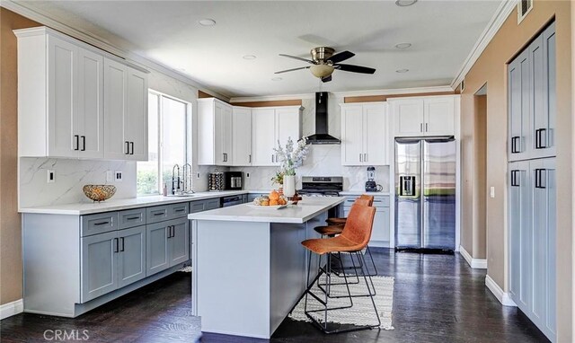 609 Raphael Dr, Corona, CA 92882 - kitchen with appliances with stainless steel finishes, wall chimney range hood, a kitchen bar, ceiling fan, and gray cabinets