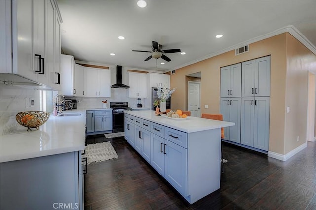 609 Raphael Dr, Corona, CA 92882 - kitchen with wall chimney exhaust hood, stove, ceiling fan, dark wood-style floors, and tasteful backsplash