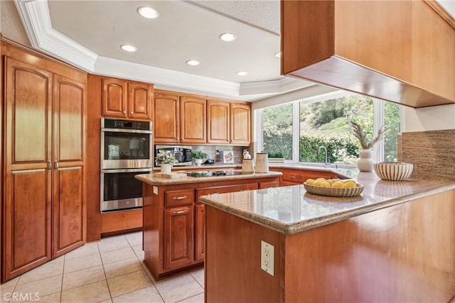 24615 Kings Rd, Laguna Niguel, CA 92677 - kitchen with stainless steel appliances, light stone counters, tasteful backsplash, brown cabinetry, and a tray ceiling
