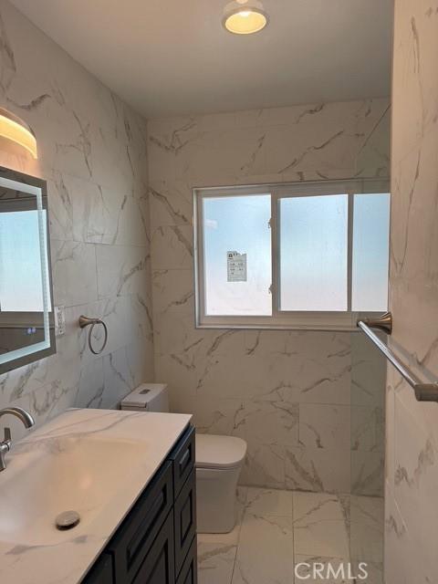 14516 Florita Rd, La Mirada, CA 90638 - bathroom with marble look tile flooring, plenty of natural light, vanity, and a marble finish shower