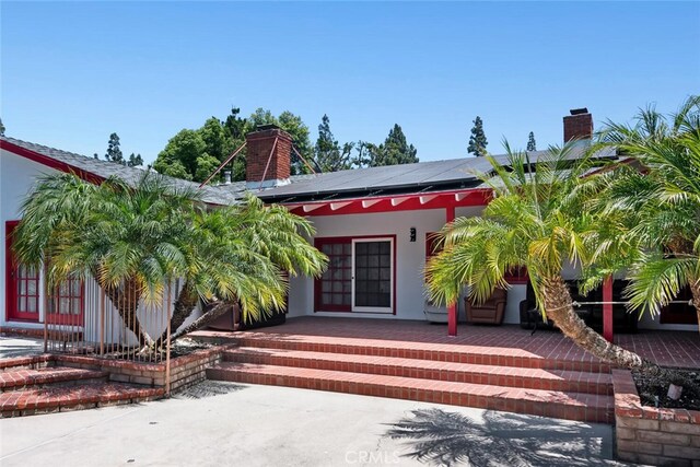10225 Donna Ave, Northridge, CA 91324 - view of exterior entry featuring a chimney, solar panels, covered porch, and stucco siding