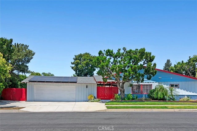 10225 Donna Ave, Northridge, CA 91324 - single story home with solar panels, an attached garage, concrete driveway, and board and batten siding