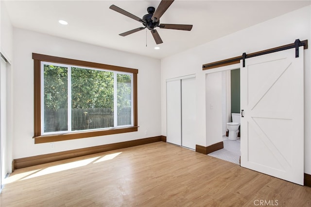 3141 Locust St, Riverside, CA 92501 - unfurnished bedroom featuring a barn door, wood finished floors, recessed lighting, connected bathroom, and a ceiling fan