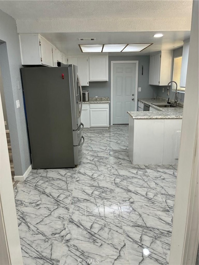 15400 Don Roberto Rd, Victorville, CA 92394 - kitchen with freestanding refrigerator, light marble finish flooring, white cabinets, a textured ceiling, and a peninsula