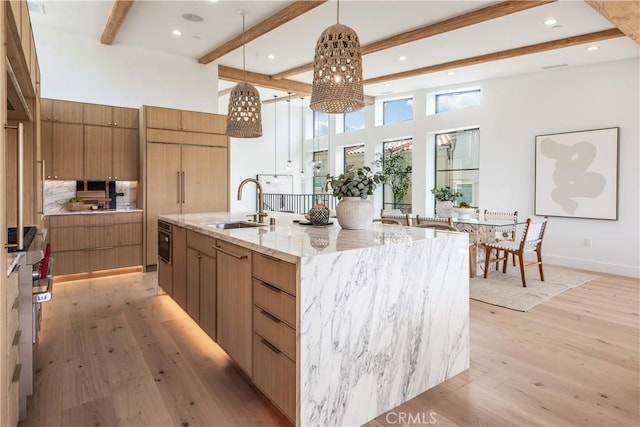 2007 Ava Ave, Hermosa Beach, CA 90254 - kitchen featuring modern cabinets, light wood-type flooring, beam ceiling, light stone counters, and a large island with sink