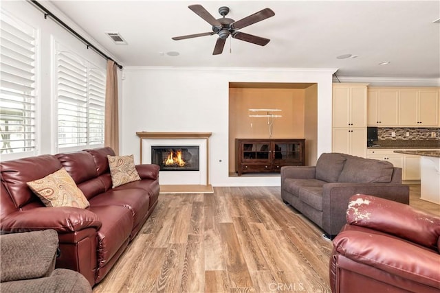 26865 Shelter Cove Ct, Menifee, CA 92585 - living room with ornamental molding, light wood finished floors, ceiling fan, and a glass covered fireplace