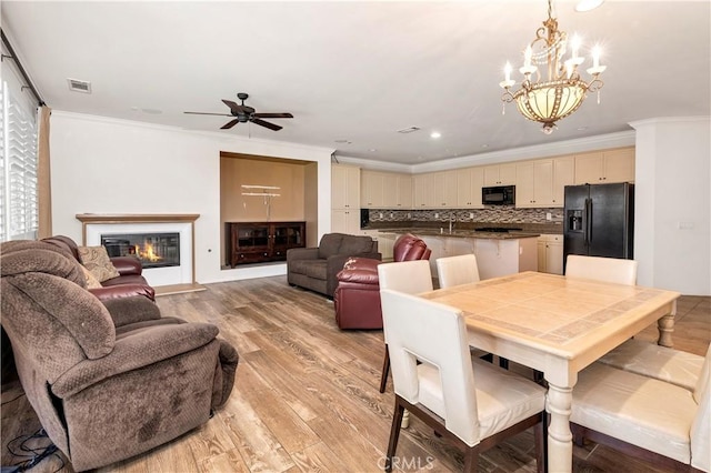 26865 Shelter Cove Ct, Menifee, CA 92585 - dining space with a chandelier, ceiling fan, light wood-style floors, crown molding, and a glass covered fireplace