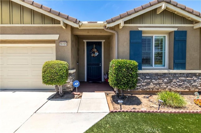 26865 Shelter Cove Ct, Menifee, CA 92585 - property entrance featuring an attached garage, stucco siding, board and batten siding, and driveway