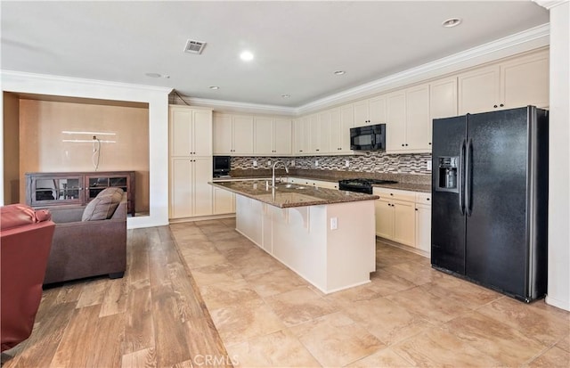 26865 Shelter Cove Ct, Menifee, CA 92585 - kitchen featuring black appliances, ornamental molding, a kitchen island with sink, dark stone countertops, and a breakfast bar area