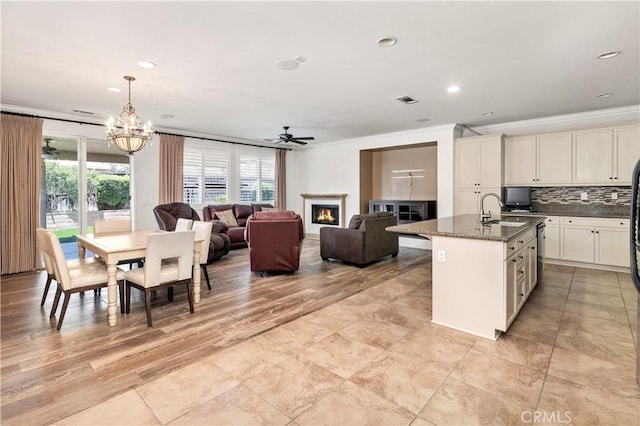 26865 Shelter Cove Ct, Menifee, CA 92585 - kitchen with crown molding, a warm lit fireplace, a chandelier, plenty of natural light, and decorative backsplash