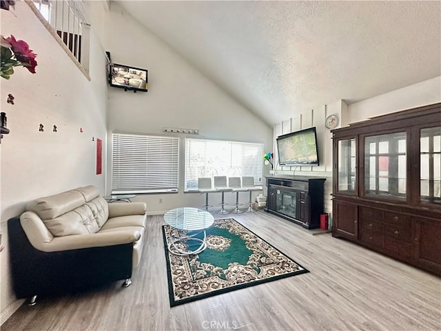 17105 Holmes Cir, Cerritos, CA 90703 - living area with high vaulted ceiling, wood finished floors, a glass covered fireplace, and a textured ceiling