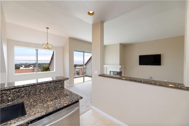 54 Los Cabos, Dana Point, CA 92629 - kitchen featuring dishwasher, dark stone counters, a glass covered fireplace, a chandelier, and vaulted ceiling
