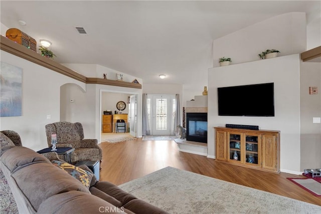 10776 Joshua St, Oak Hills, CA 92344 - living room featuring a multi sided fireplace, wood finished floors, arched walkways, and vaulted ceiling