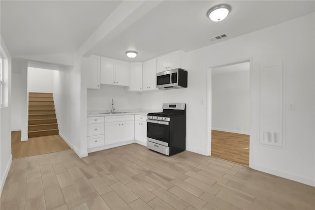 3032 Cogswell Rd, El Monte, CA 91732 - kitchen with stainless steel appliances, light countertops, white cabinets, and light wood-type flooring