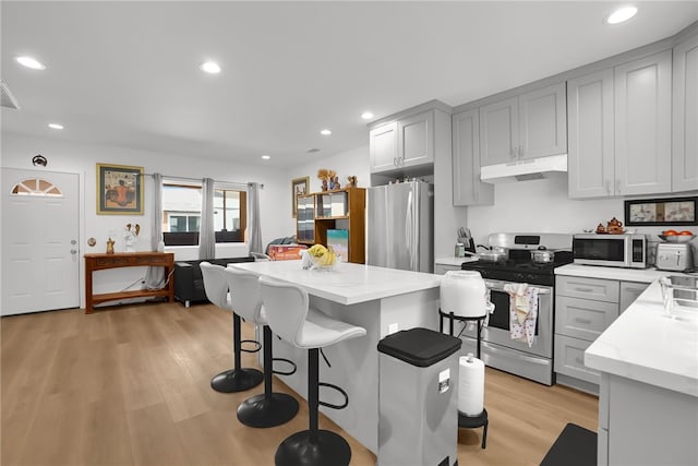 3032 Cogswell Rd, El Monte, CA 91732 - kitchen featuring appliances with stainless steel finishes, under cabinet range hood, light wood-style floors, a breakfast bar, and gray cabinetry