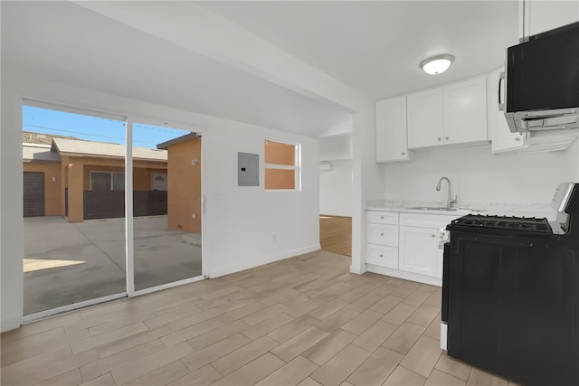 3032 Cogswell Rd, El Monte, CA 91732 - kitchen featuring black gas range, stainless steel microwave, electric panel, white cabinetry, and light wood finished floors