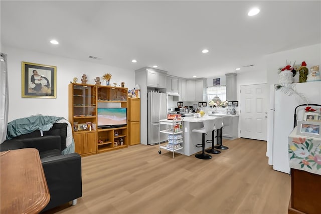 3032 Cogswell Rd, El Monte, CA 91732 - kitchen with freestanding refrigerator, a kitchen bar, light countertops, fridge, and light wood finished floors
