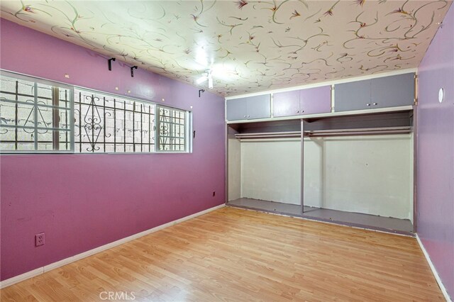 7134 Stansbury Ave, Van Nuys, CA 91405 - unfurnished bedroom featuring multiple windows, light wood-style flooring, and a closet