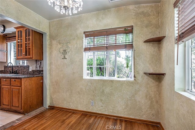 7134 Stansbury Ave, Van Nuys, CA 91405 - kitchen with light wood-style floors, brown cabinets, glass insert cabinets, and a chandelier