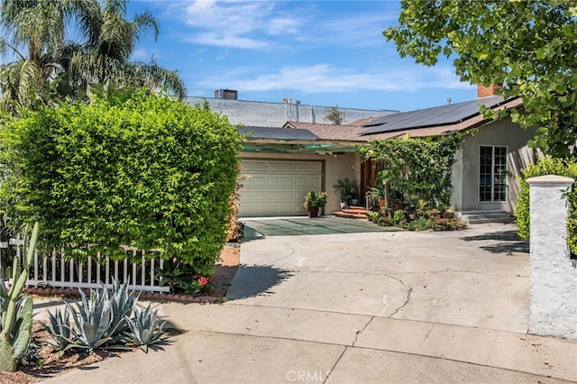 7134 Stansbury Ave, Van Nuys, CA 91405 - view of property hidden behind natural elements with stucco siding, driveway, an attached garage, solar panels, and a chimney
