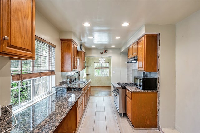 7134 Stansbury Ave, Van Nuys, CA 91405 - kitchen with black microwave, high end stove, brown cabinetry, dark stone countertops, and recessed lighting