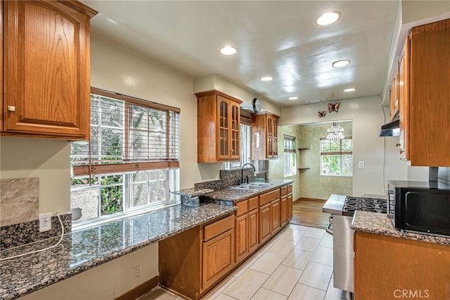7134 Stansbury Ave, Van Nuys, CA 91405 - kitchen with black microwave, brown cabinets, gas range, glass insert cabinets, and under cabinet range hood