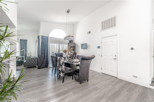 13800 Glenoaks Blvd, Sylmar, CA 91342 - dining room featuring light wood-type flooring, a chandelier, and a high ceiling