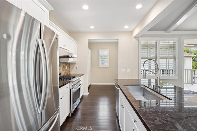 72 Peony, Irvine, CA 92618 - kitchen featuring appliances with stainless steel finishes, under cabinet range hood, dark stone counters, dark wood-type flooring, and white cabinetry