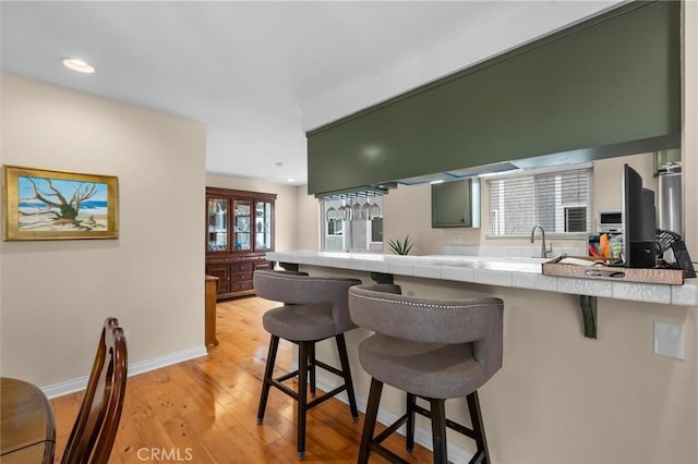 504 Harkness Ln Unit 1, Redondo Beach, CA 90278 - kitchen featuring tile countertops, a breakfast bar, a peninsula, light wood finished floors, and recessed lighting