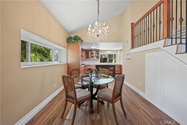 5706 E Bryce Ave, Orange, CA 92867 - dining room with wood finished floors, high vaulted ceiling, a chandelier, and stairway