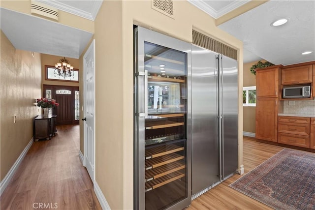 5706 E Bryce Ave, Orange, CA 92867 - kitchen with stainless steel microwave, light wood-style flooring, a chandelier, crown molding, and brown cabinets