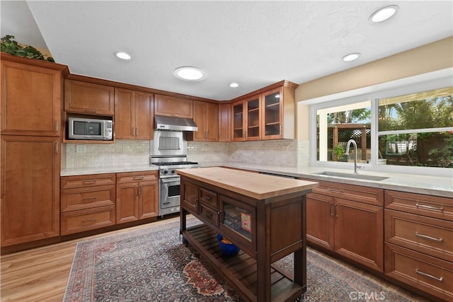 5706 E Bryce Ave, Orange, CA 92867 - kitchen featuring appliances with stainless steel finishes, under cabinet range hood, butcher block counters, glass insert cabinets, and brown cabinetry