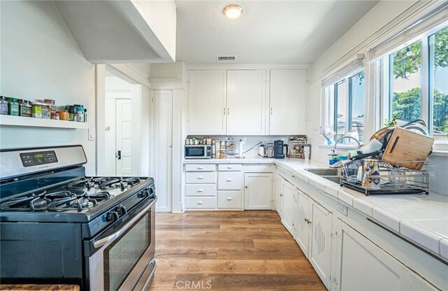 201 S Spruce St, Montebello, CA 90640 - kitchen with stainless steel appliances, white cabinets, tile counters, and light wood-style floors