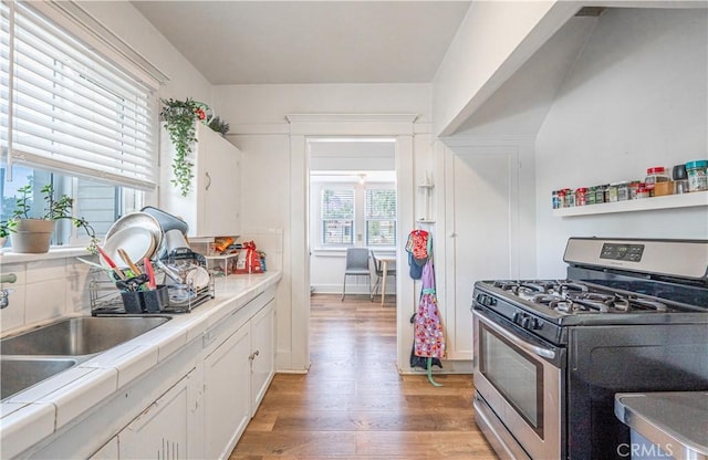 201 S Spruce St, Montebello, CA 90640 - kitchen featuring stainless steel gas range, tile counters, light wood finished floors, and white cabinets