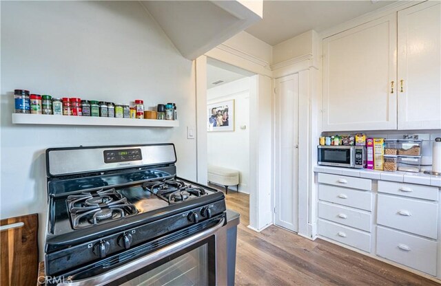 201 S Spruce St, Montebello, CA 90640 - kitchen with appliances with stainless steel finishes, tile counters, wood finished floors, and white cabinets