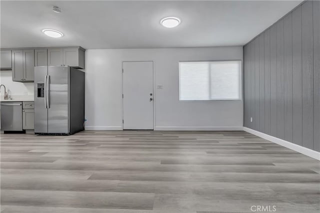 3265 Santa Fe Ave Unit 145, Long Beach, CA 90810 - kitchen with stainless steel appliances, gray cabinetry, light wood-style floors, light countertops, and wood walls