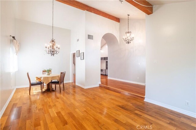 24302 Vista Ridge Dr, Valencia, CA 91355 - dining area featuring a chandelier, arched walkways, light wood-type flooring, beam ceiling, and high vaulted ceiling