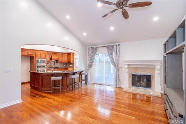 24302 Vista Ridge Dr, Valencia, CA 91355 - kitchen featuring appliances with stainless steel finishes, brown cabinetry, open floor plan, a ceiling fan, and a breakfast bar