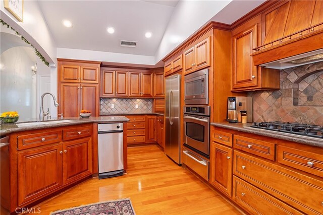 24302 Vista Ridge Dr, Valencia, CA 91355 - kitchen with appliances with stainless steel finishes, a warming drawer, premium range hood, brown cabinetry, and light wood finished floors